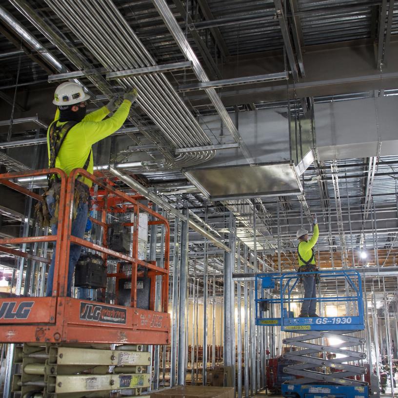 MEP crews installing overhead conduit and ductwork
